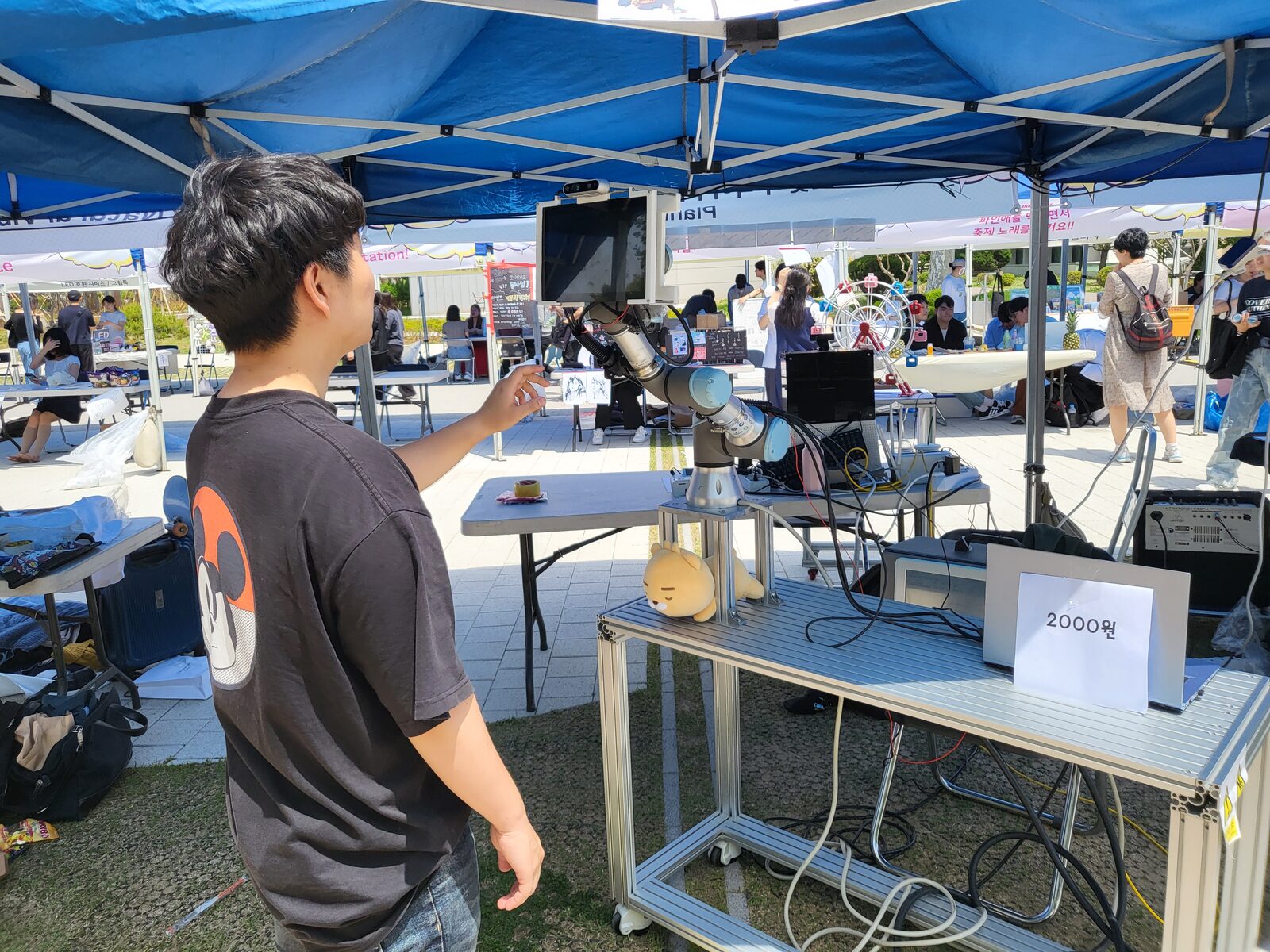 A visitor standing in front of the Snapbot booth while the robot arm takes their photo