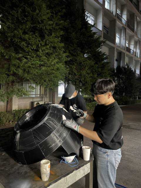 Team member sanding and finishing the Hongdo robot head shell during fabrication.